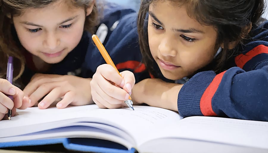 Second grader's hands writing persuasive opinion statement with colorful markers on poster board